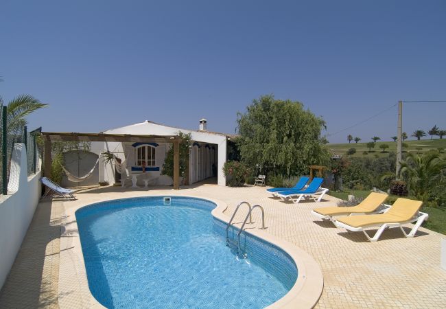 Kidney-shaped pool next to Vivenda Trilio with spacious terrace, sun loungers and covered seating area