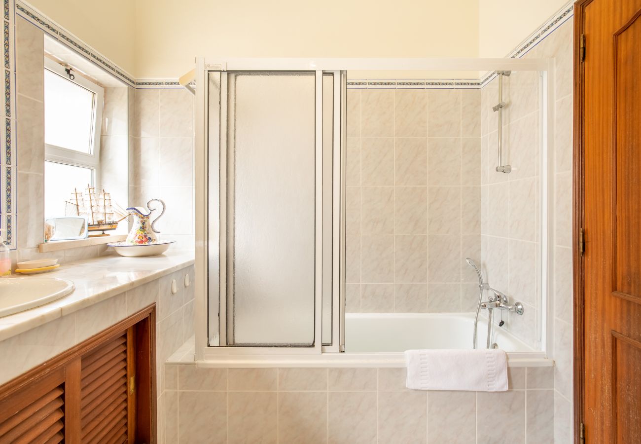 Classic Bathroom with Double Vanity and Bidet A classic bathroom with light tiles, wood cabinets, a double vanity, and bidet.