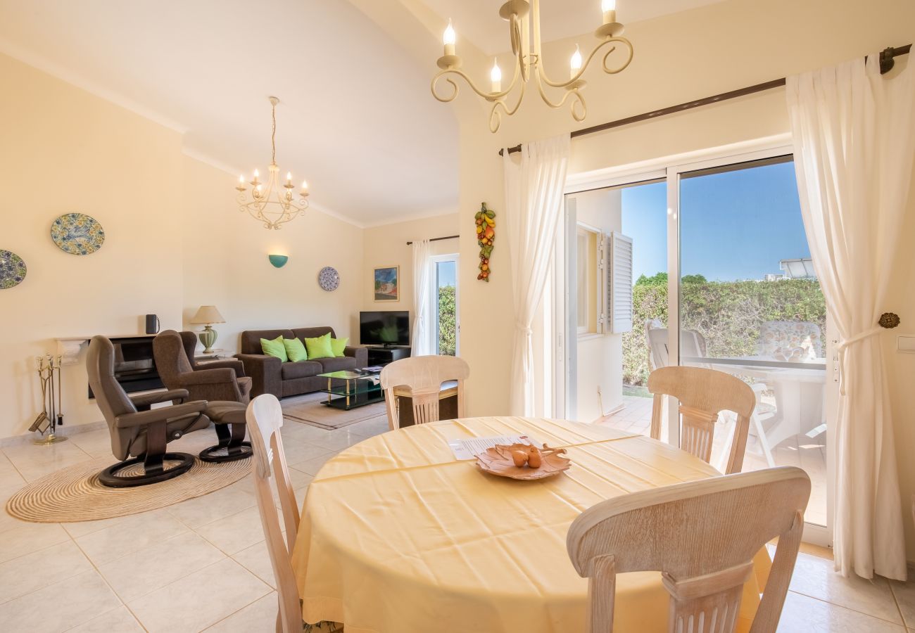Bright interior with a dining and living area and pool view. View from a dining table of a living area with a sofa and an outdoor terrace with a pool.