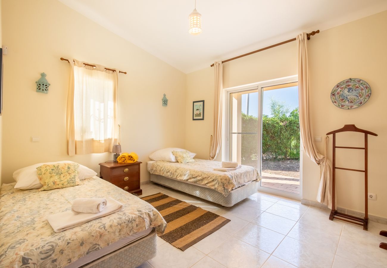 Cozy Bedroom with Natural Light A bright bedroom with two single beds, two nightstands with lamps, and a window.