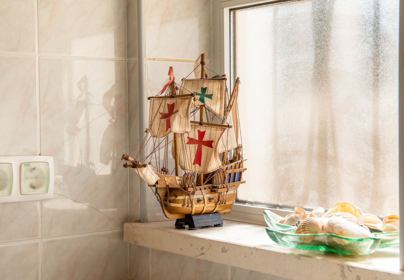 Maritime Decor on Windowsill A model ship and seashells in a glass bowl on a windowsill.