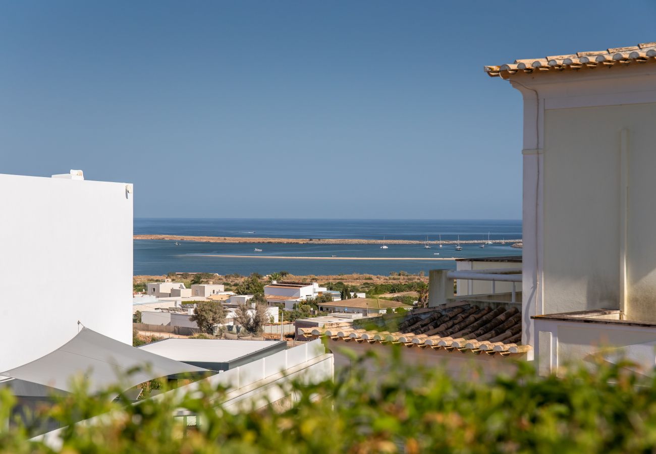 Balcony view over a coastal town to a tranquil bay. Seaview from a balcony over a coastal town, a bay with boats, and a clear blue sky.