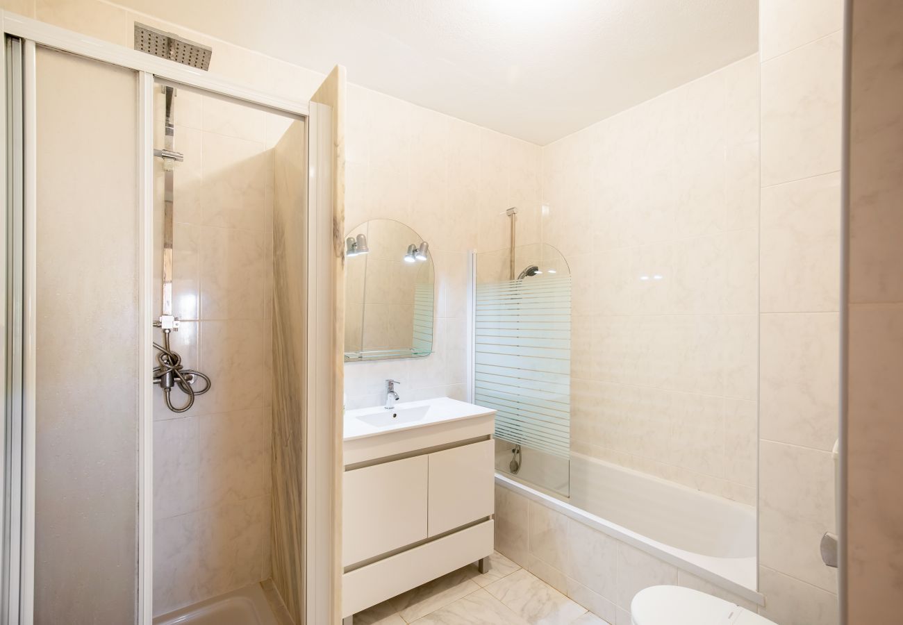 Bright, Modern Bathroom with Separate Shower and Bathtub Bathroom with beige tiles, white vanity, mirror, enclosed shower with sliding door, and a bathtub.