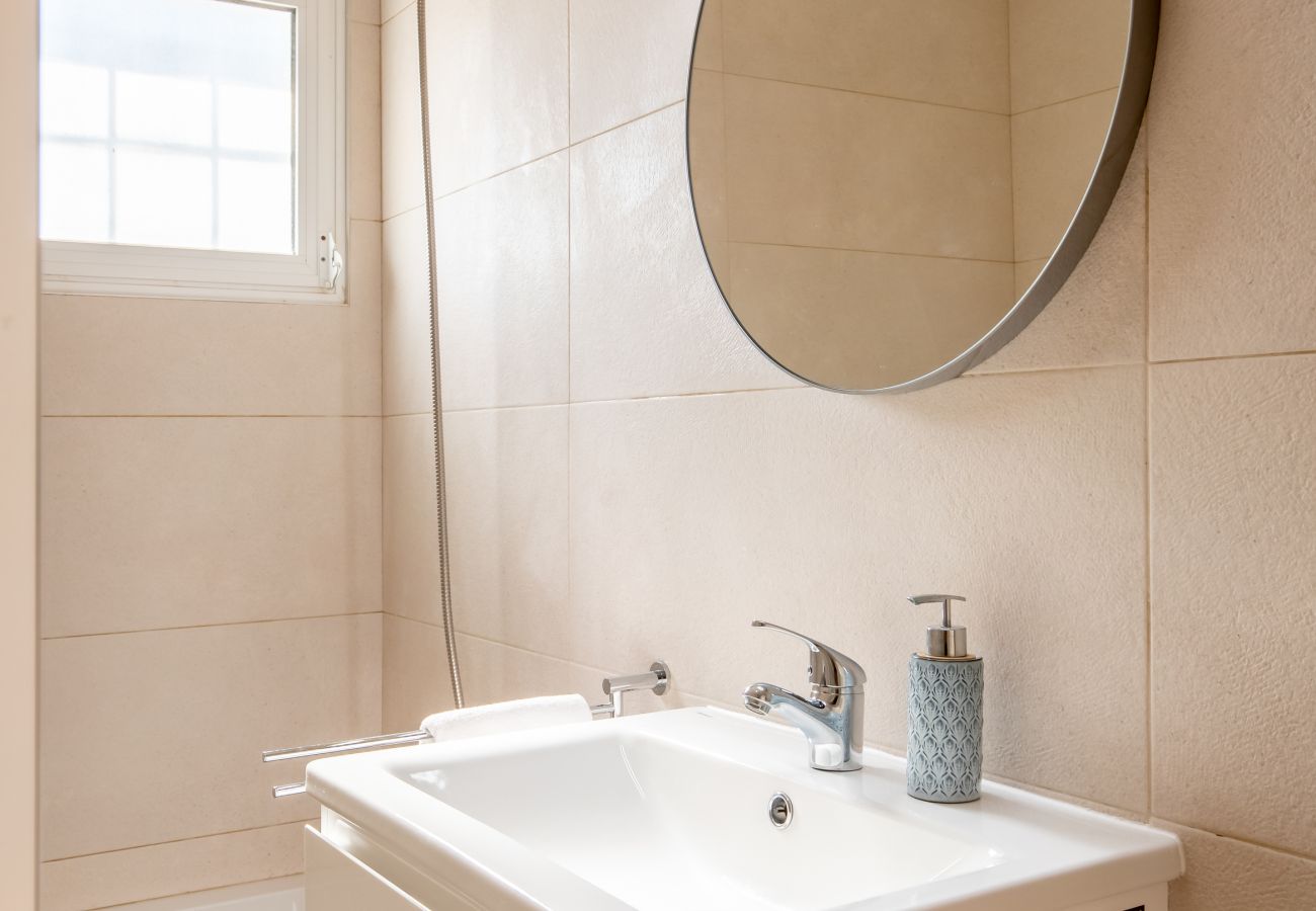 Bathroom with Vanity and Mirror Bathroom with a white vanity, a round mirror, and beige tiles.