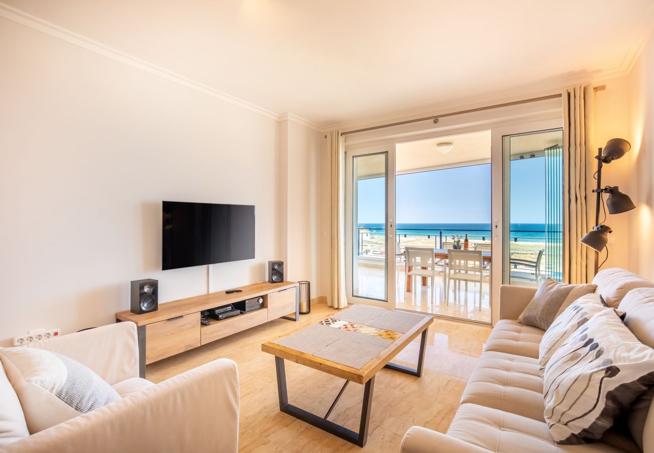 Living Room with Ocean View Balcony Access Living room with a sofa, armchair, TV, and open sliding doors leading to a balcony with ocean view.