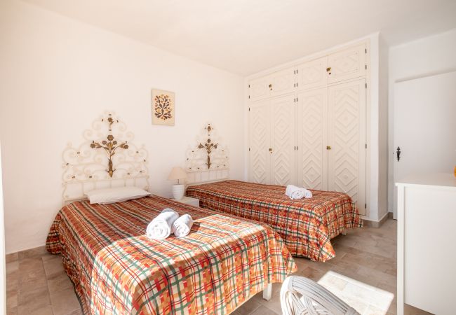 Quarto com duas Camas de Solteiro e Guarda-roupa Quarto com duas camas de solteiro, colchas xadrez e um guarda-roupa branco.