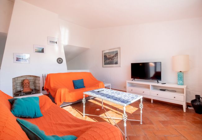 Sala de Estar com Lareira e Televisão Sala de estar com lareira, sofás laranja, mesa de centro e televisão.
