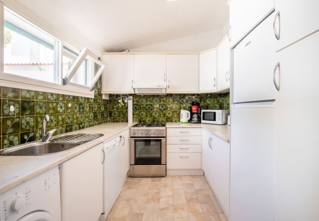 Cozinha Totalmente Equipada com Máquina de Lavar Cozinha com armários brancos, azulejos verdes e eletrodomésticos.