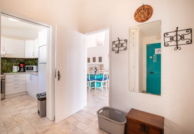 Corredor com Vista para a Cozinha e Área de Jantar Corredor com porta aberta para a cozinha, área de jantar ao fundo e porta turquesa.