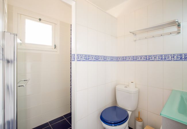 Casa de Banho com Azulejos Azuis e Sanita Casa de banho pequena com sanita, faixa de azulejos azul e branco e lavatório de canto verde.