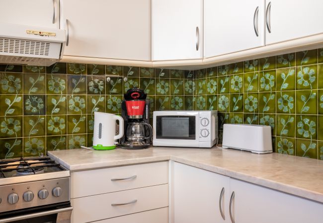 Balcão da Cozinha com Eletrodomésticos Balcão da cozinha com azulejos verdes, micro-ondas, máquina de café e torradeira.
