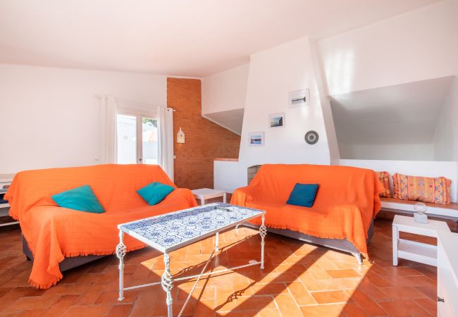 Sala de Estar com Escadas para a Área de Jantar Sala de estar com sofás laranja, mesa de centro e escadas.