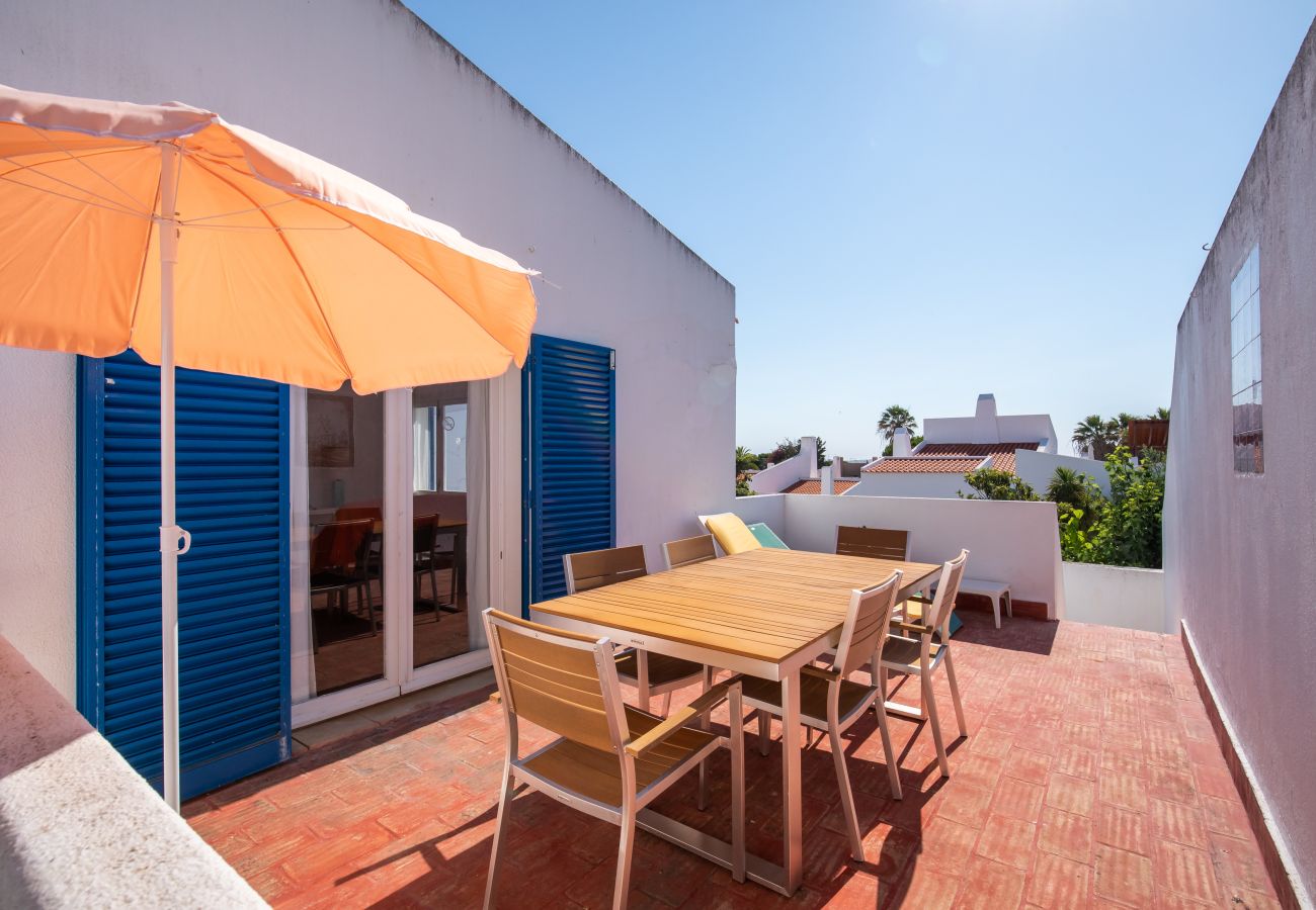 Terraço no Telhado com Mesa e Guarda-sol Terraço ensolarado com mesa de madeira, cadeiras e guarda-sol laranja.