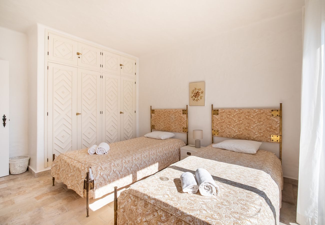 Quarto com Duas Camas de Solteiro e Guarda-Roupa Quarto com duas camas de solteiro, cabeceiras douradas e guarda-roupa branco com padrão de losangos.