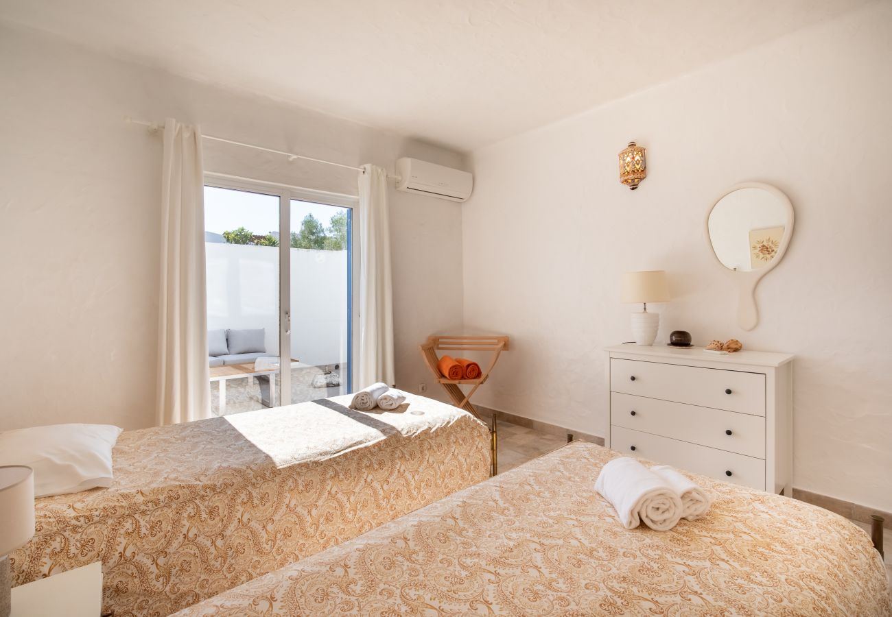 Quarto com Duas Camas de Solteiro e Acesso ao Pátio Quarto com duas camas de solteiro, cómoda branca, espelho redondo e porta de correr para o pátio.