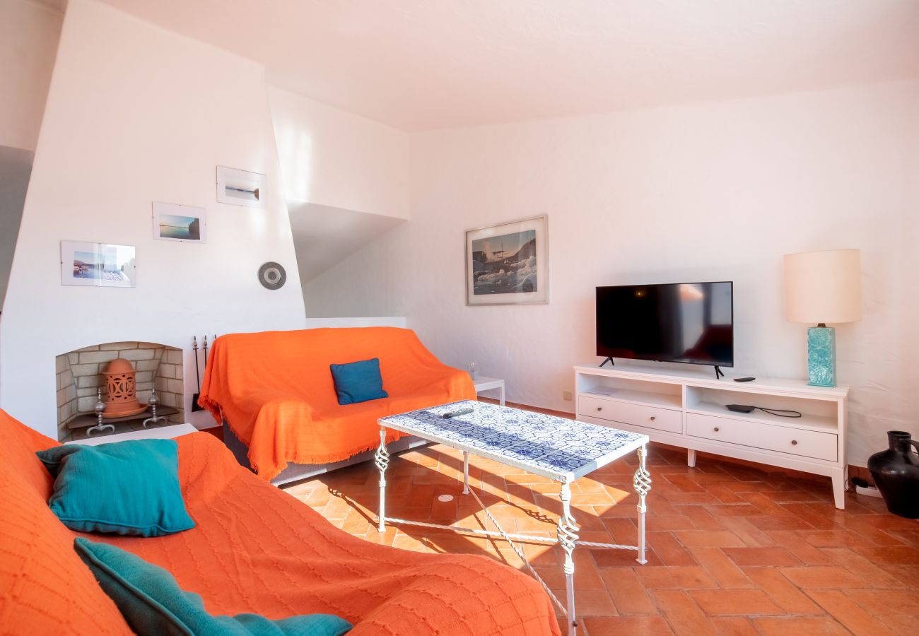 Sala de Estar com Lareira e Televisão Sala de estar com lareira, sofás laranja, mesa de centro e televisão.