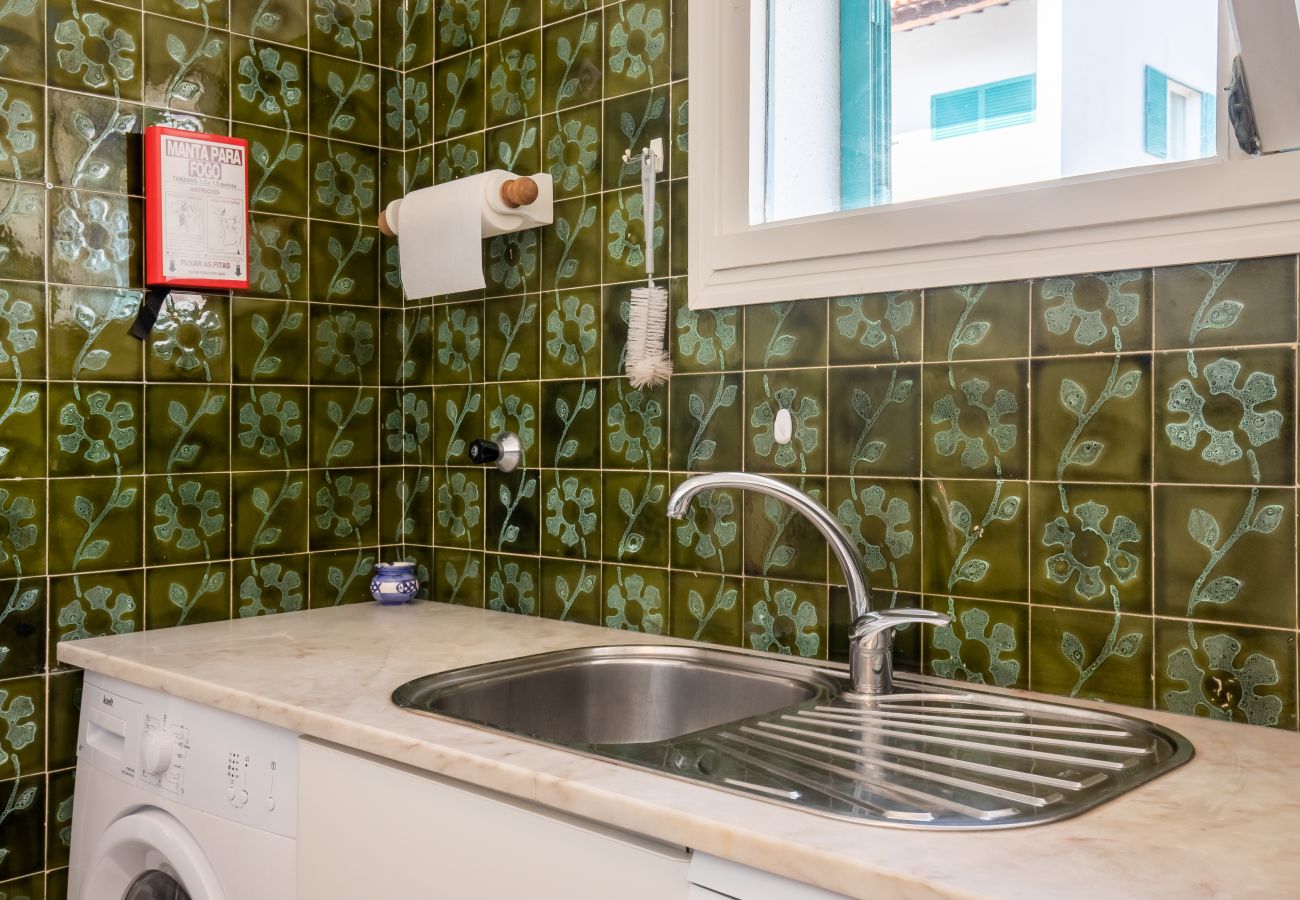 Lava-loiça e Máquina de Lavar Roupa da Cozinha Balcão da cozinha com lava-loiça, máquina de lavar roupa e azulejos verdes.