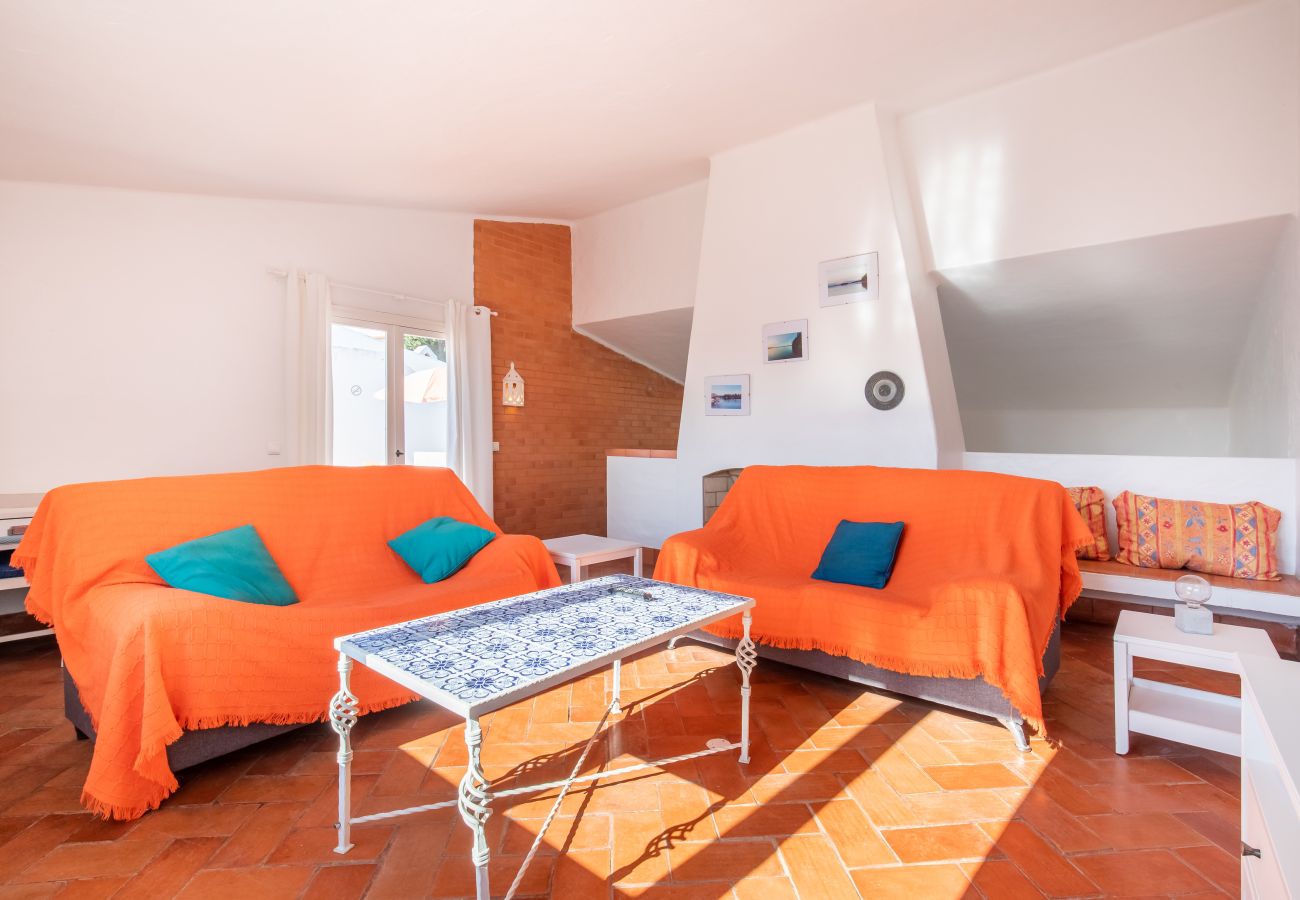 Sala de Estar com Escadas para a Área de Jantar Sala de estar com sofás laranja, mesa de centro e escadas.
