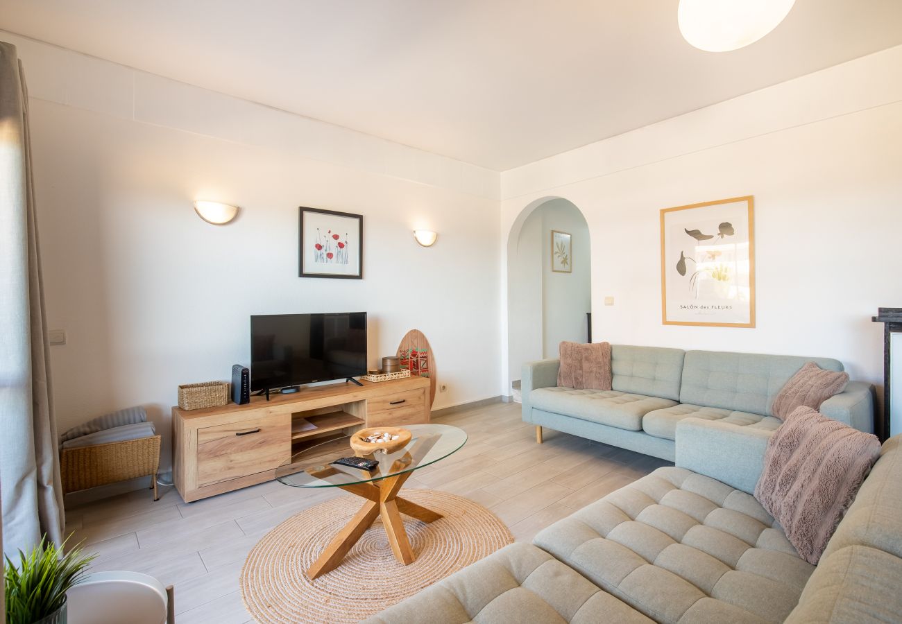 Sala de Estar Clara com Sofás Modernos e Elegantes Sala de estar ampla com dois sofás verdes, móvel TV de madeira, mesa de centro, tapete de juta e arco.