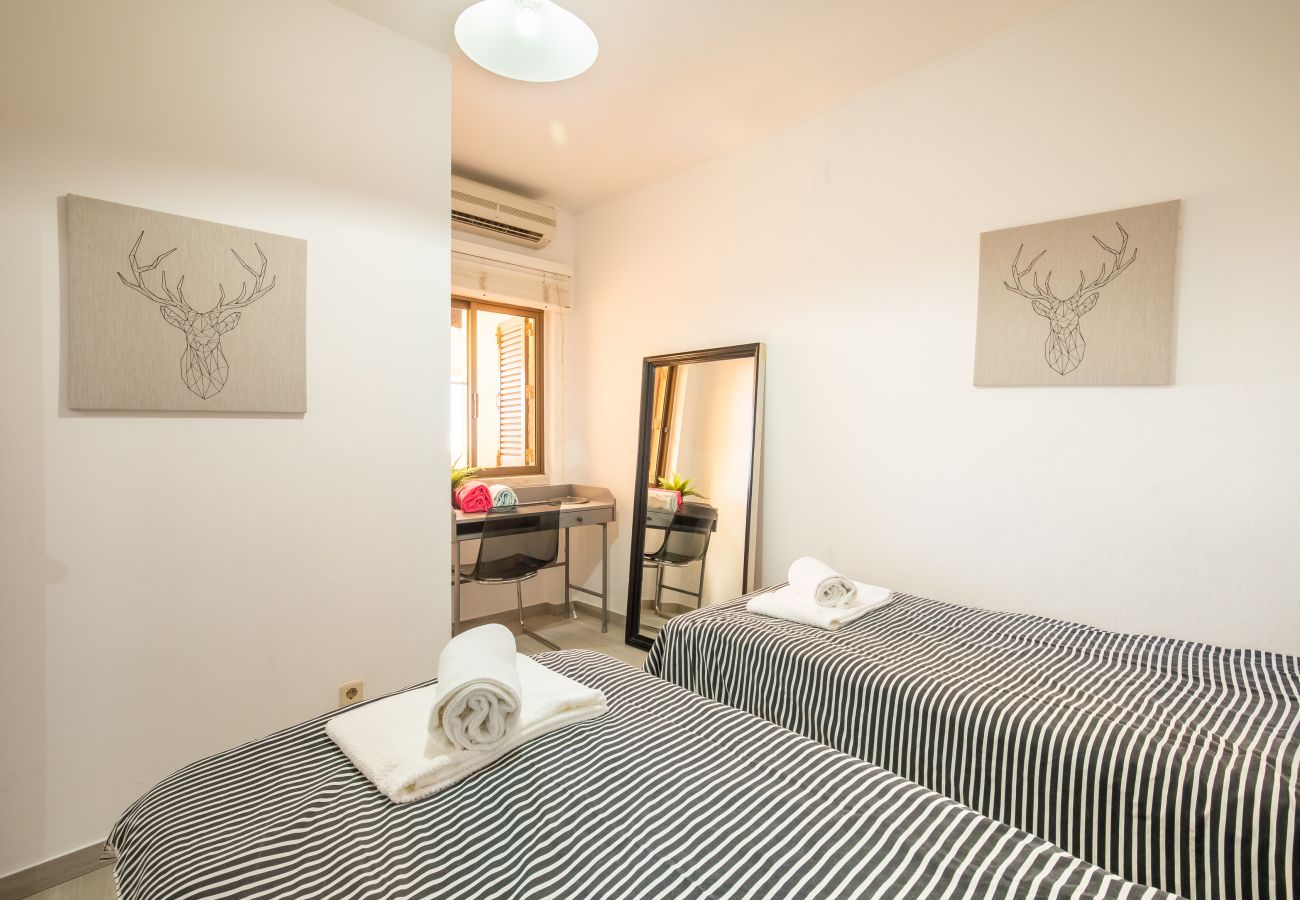 Quarto Twin com Riscas e Decoração Moderna Quarto twin claro com camas listradas, arte de veado, espelho de corpo inteiro e secretária junto à janela.