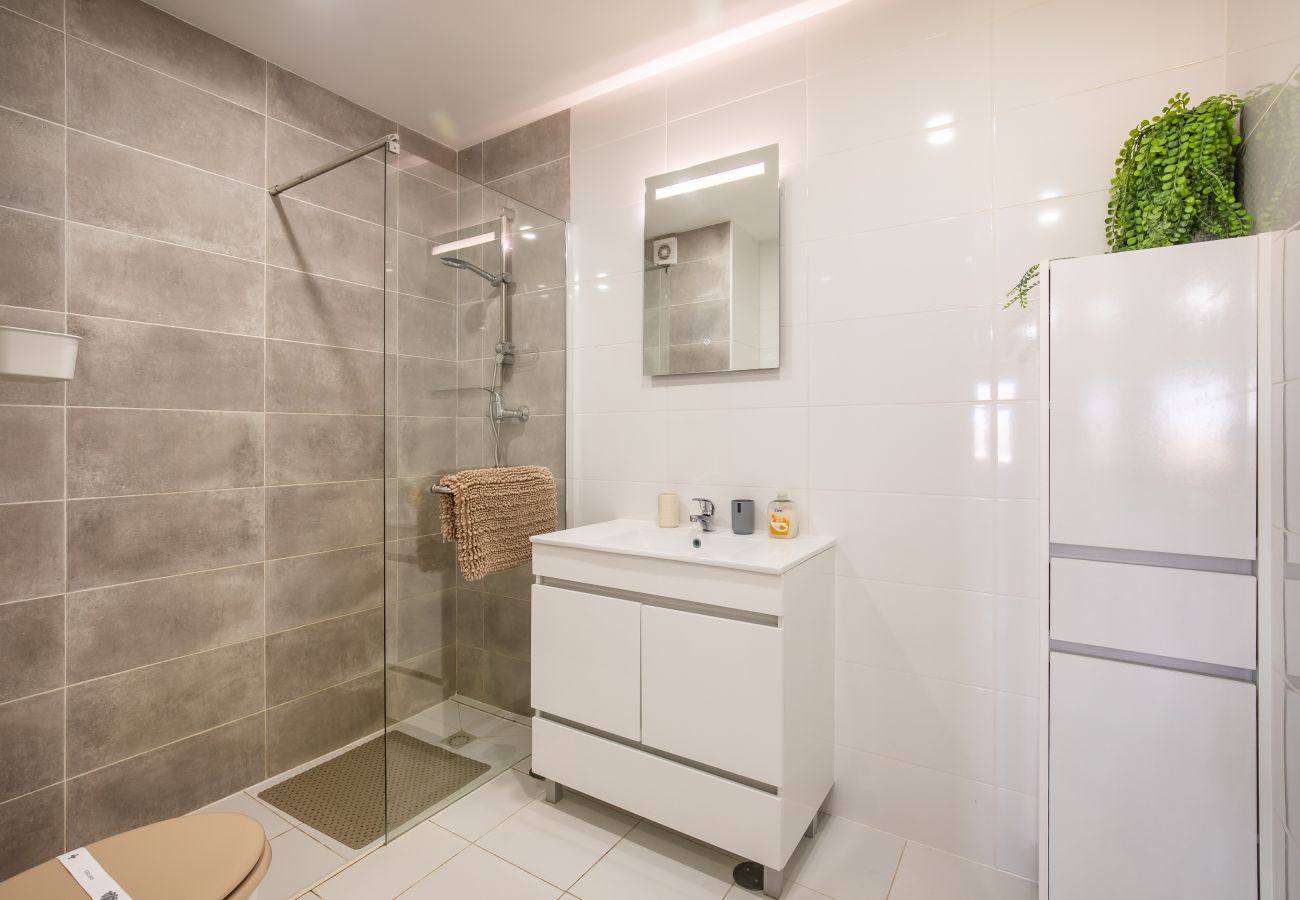 Casa de Banho Moderna com Duche Cinzento e Branco Casa de banho moderna com duche de azulejos cinzentos, lavatório branco, espelho e armários brancos.