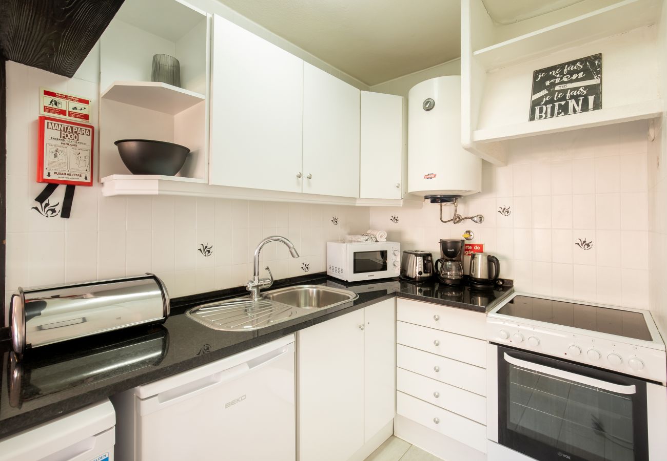 Cozinha Brilhante e Funcional com Design Moderno Cozinha em L compacta com armários brancos, bancada preta e eletrodomésticos como forno, fogão e micro-ondas.