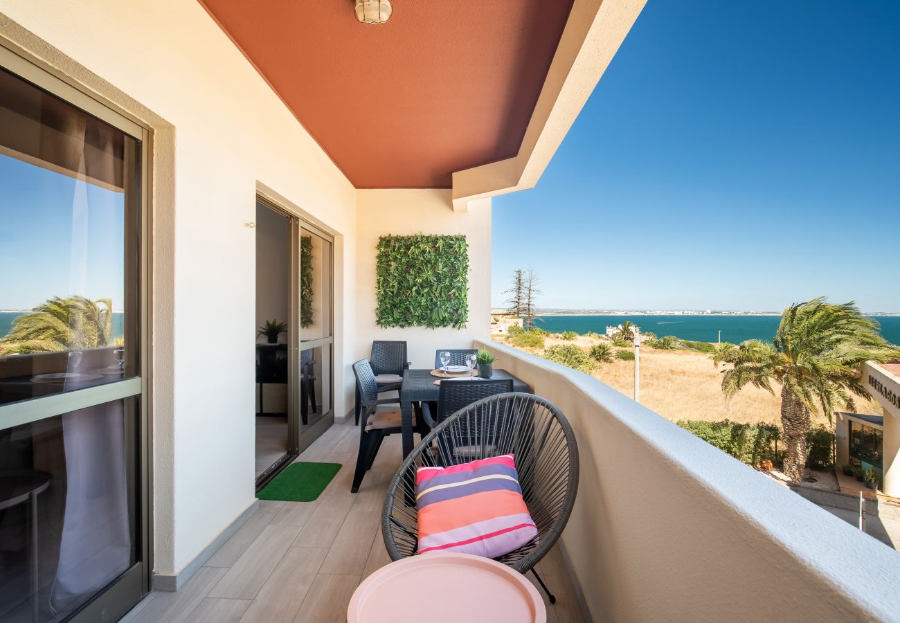 Varanda de Lazer com Vista Mar e Toque de Terracota Varanda com mesa e poltrona, teto terracota, palmeiras e vista ampla para o mar azul sob céu limpo.