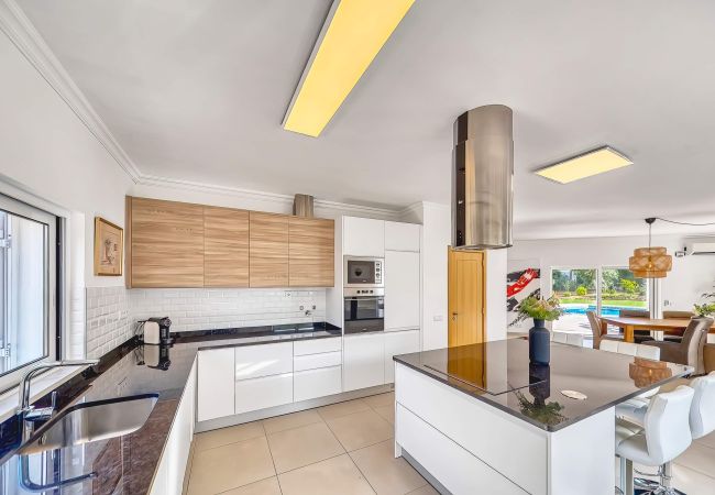 Cozinha ampla e em plano aberto na Villa Larissa Cozinha ampla e luminosa com ilha de cozinha