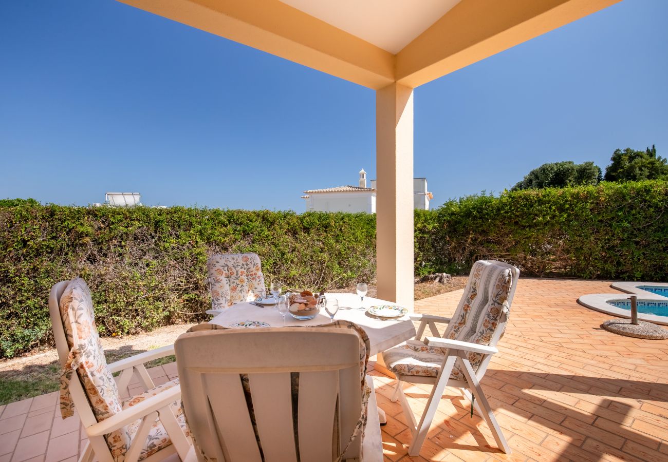 Gedeckte Terrasse mit Essbereich und Poolblick. Gedeckter Esstisch auf einer überdachten Terrasse mit Poolblick und grüner Hecke.