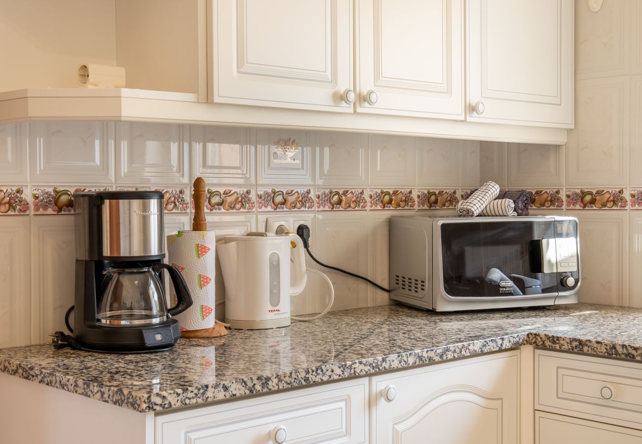 Gut ausgestattete Küche mit Granit-Arbeitsplatten Eine Küche mit Granit-Arbeitsplatten, weißen Schränken und Haushaltsgeräten, darunter eine Kaffeemaschine und Mikrowelle.