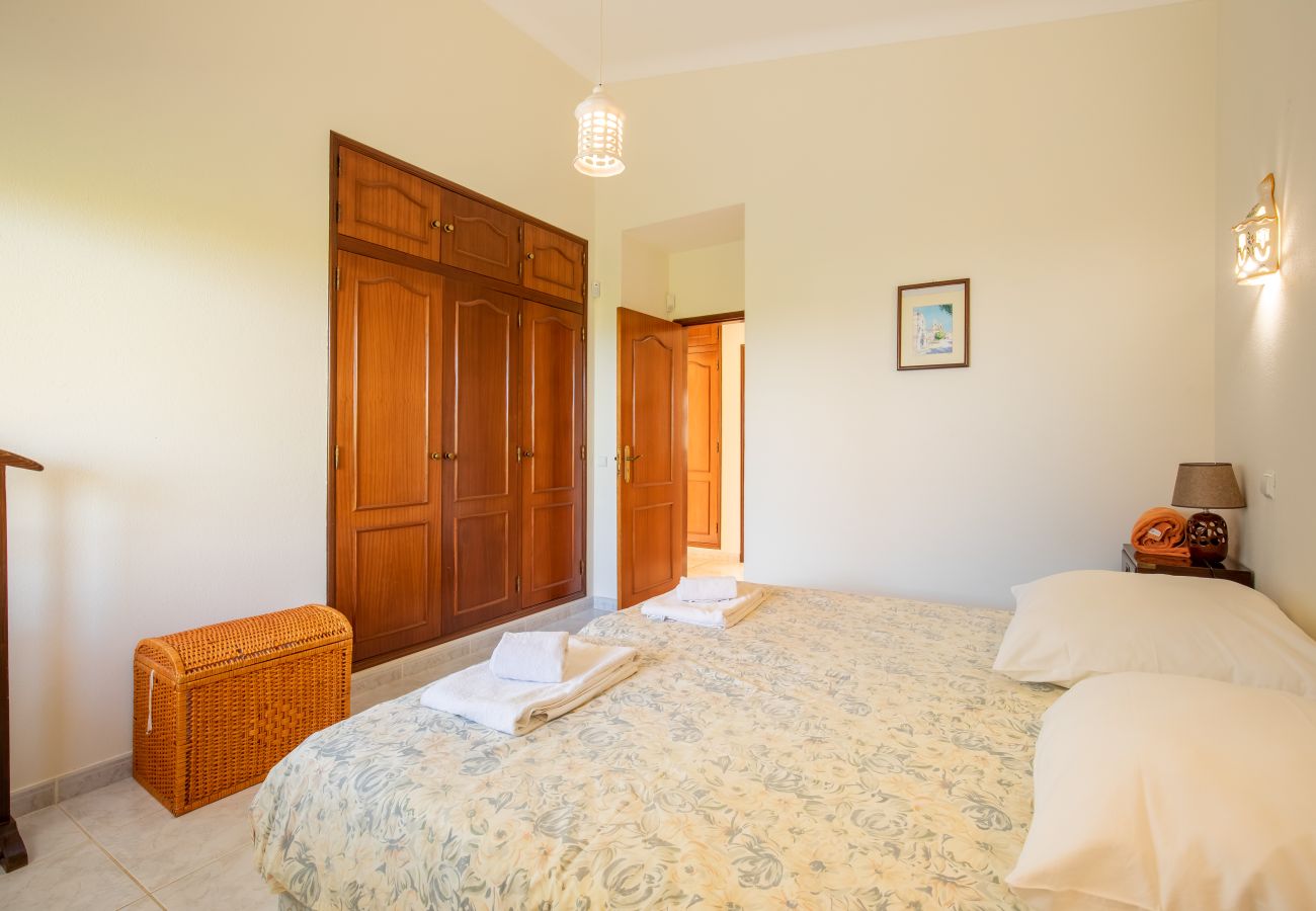 Gemütliches Schlafzimmer mit zwei Betten und Schrank Ein helles Schlafzimmer mit zwei Einzelbetten, einem großen Holzschrank, einem Nachttisch und einem Fenster.