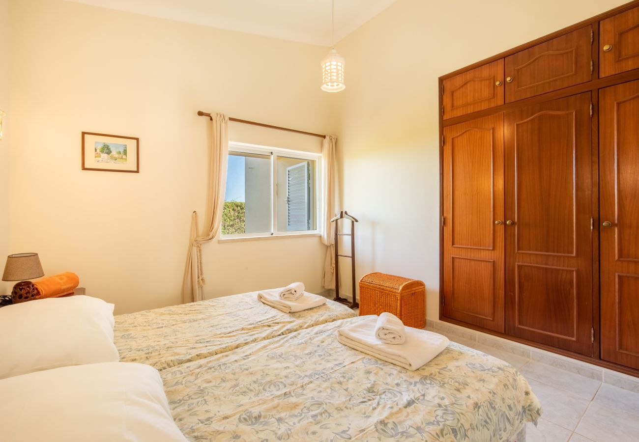 Helles Schlafzimmer mit zwei Einzelbetten und Holzschrank Ein helles Schlafzimmer mit zwei Einzelbetten, einem großen Holzschrank und einem Fenster, das Tageslicht hereinlässt.