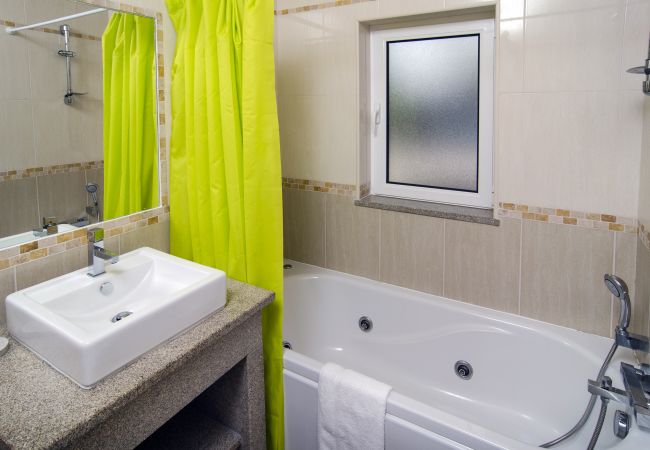 Badezimmer mit Badewanne mit Massagefunktion Badezimmer mit Badewanne in Vivenda Zabra und neongrünem Duschvorhang