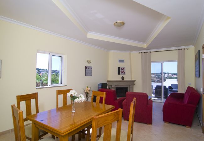Esstisch hölzerner Esstisch für sechs Personen im Wohnzimmer von Vivenda Zabra mit Aussicht vorbei an den roten Sofas und Kamin