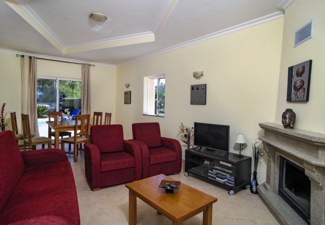 Wohnzimmer mit roten Sofas vor dem Kamin Wohnzimmer mit roten Sofas und Fernseher vor dem Kamin in Vivenda Zabra