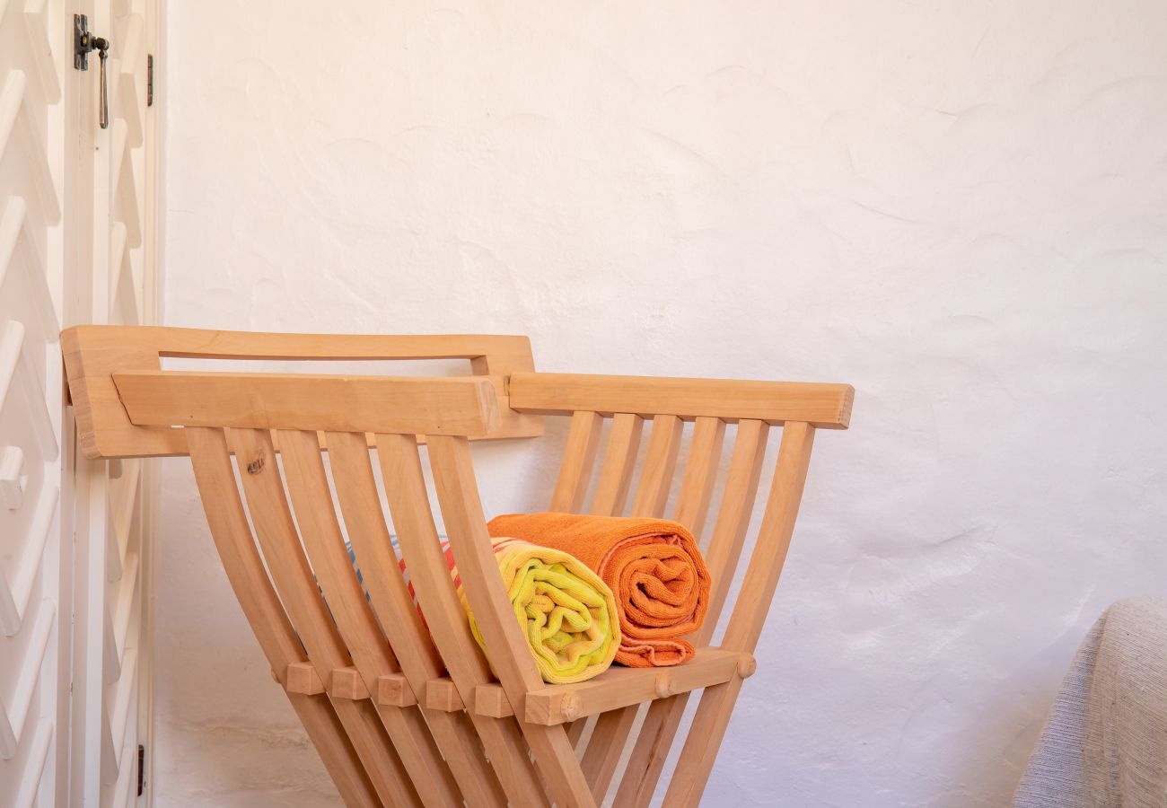 Handtuchhalter aus Holz mit gelbem und orangefarbenem Handtuch Nahaufnahme eines klappbaren Holzständers mit zwei zusammengerollten Handtüchern.