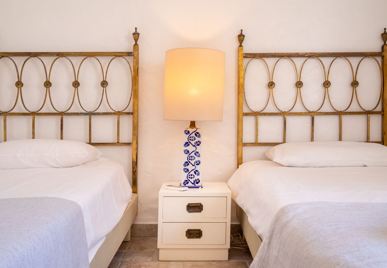 Nahaufnahme von zwei Einzelbetten mit goldenen Kopfteilen und Lampe Zwei Einzelbetten mit goldenen Metall-Kopfteilen und ein Nachttisch mit einer Lampe mit blauem Keramikfuß dazwischen.