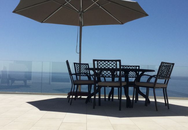 runder Esstisch mit Sonnenschirm auf großer Terrasse mit Glasgeländer und Meerblick in Villa Katiya