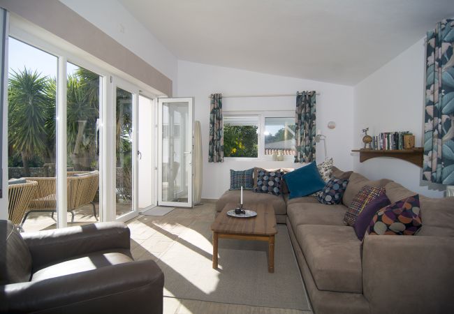 Braunes Ecksofa im Wohnzimmer mit Blick in den Garten  Braunes Ecksofa im hinteren Bereich des Wohnzimmer von Casa Palmeira mit gutem Blick in den Garten