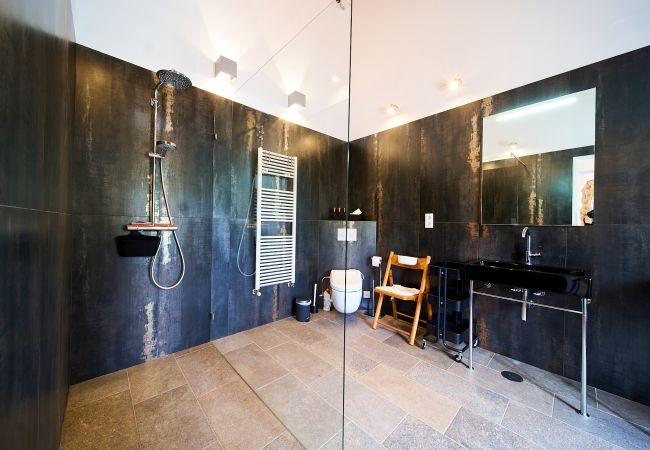 Dunkles Badezimmer mit großer Duschkabine   großes dunkel gefliestes Badezimmer mit großer Dusche, WC und schwarzem Waschbecken in Casa Palmeira