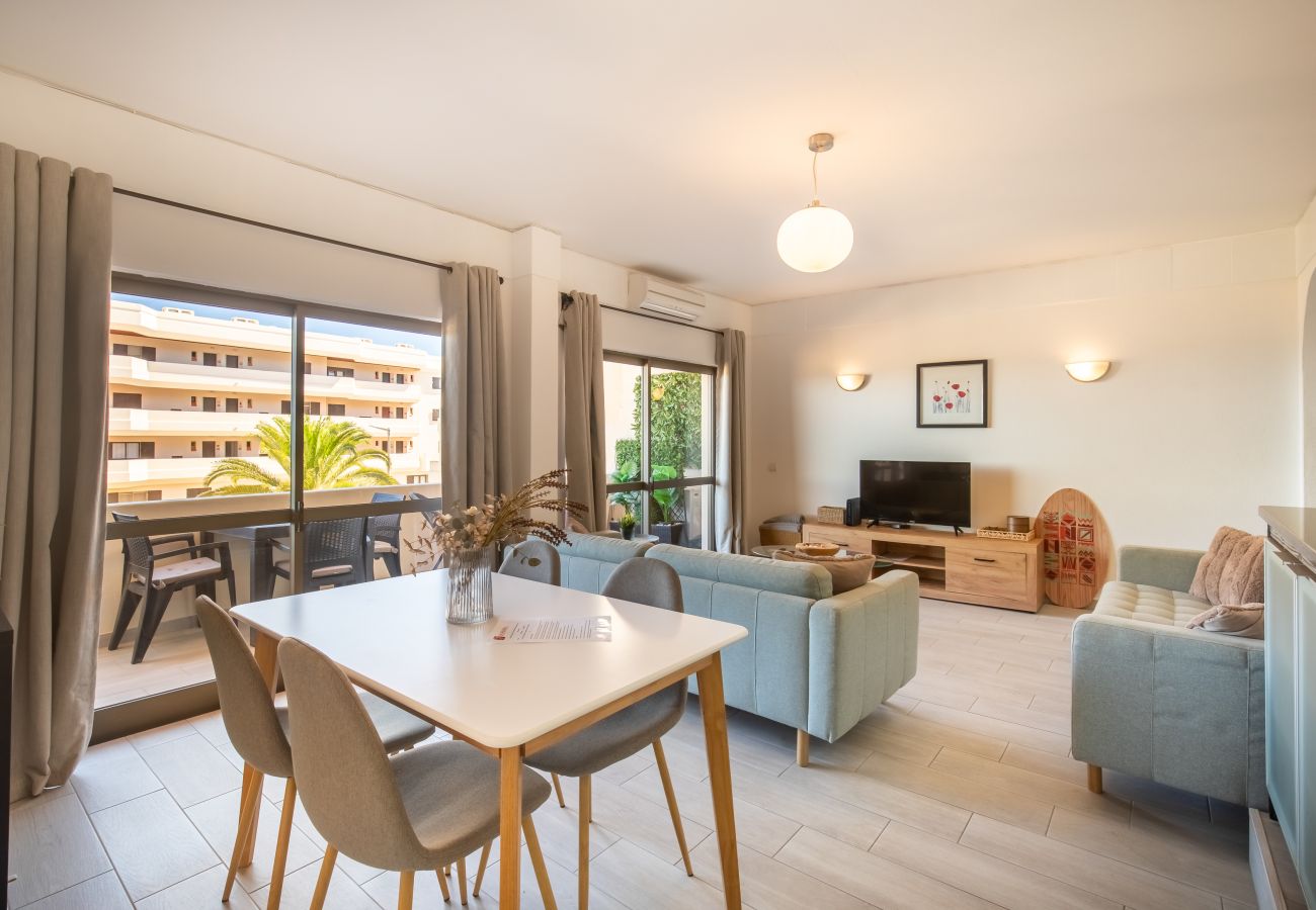 Helles Kombiniertes Wohn- und Esszimmer mit Balkon Offenes Wohn- und Esszimmer mit weißem Tisch, mintgrünen Sofas und Blick auf Balkon, Palmen und Gebäude.