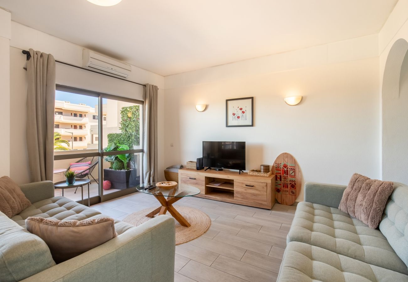 Helles Wohnzimmer mit Balkonzugang und Stil Helles Wohnzimmer mit zwei mintgrünen Sofas, TV-Möbel und Glastür zu einem möblierten Balkon mit Pflanzen.