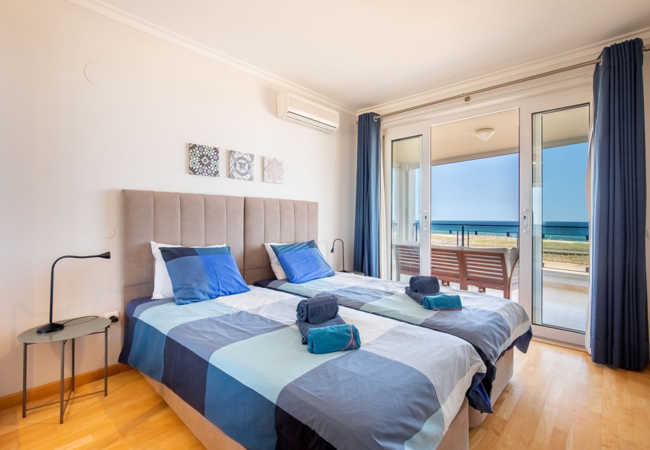 Ihr Komfortables Zweibettzimmer mit Meerblick-Balkon Schlafzimmer mit zwei Einzelbetten, blauer Bettwäsche und einem Balkon mit Meerblick.