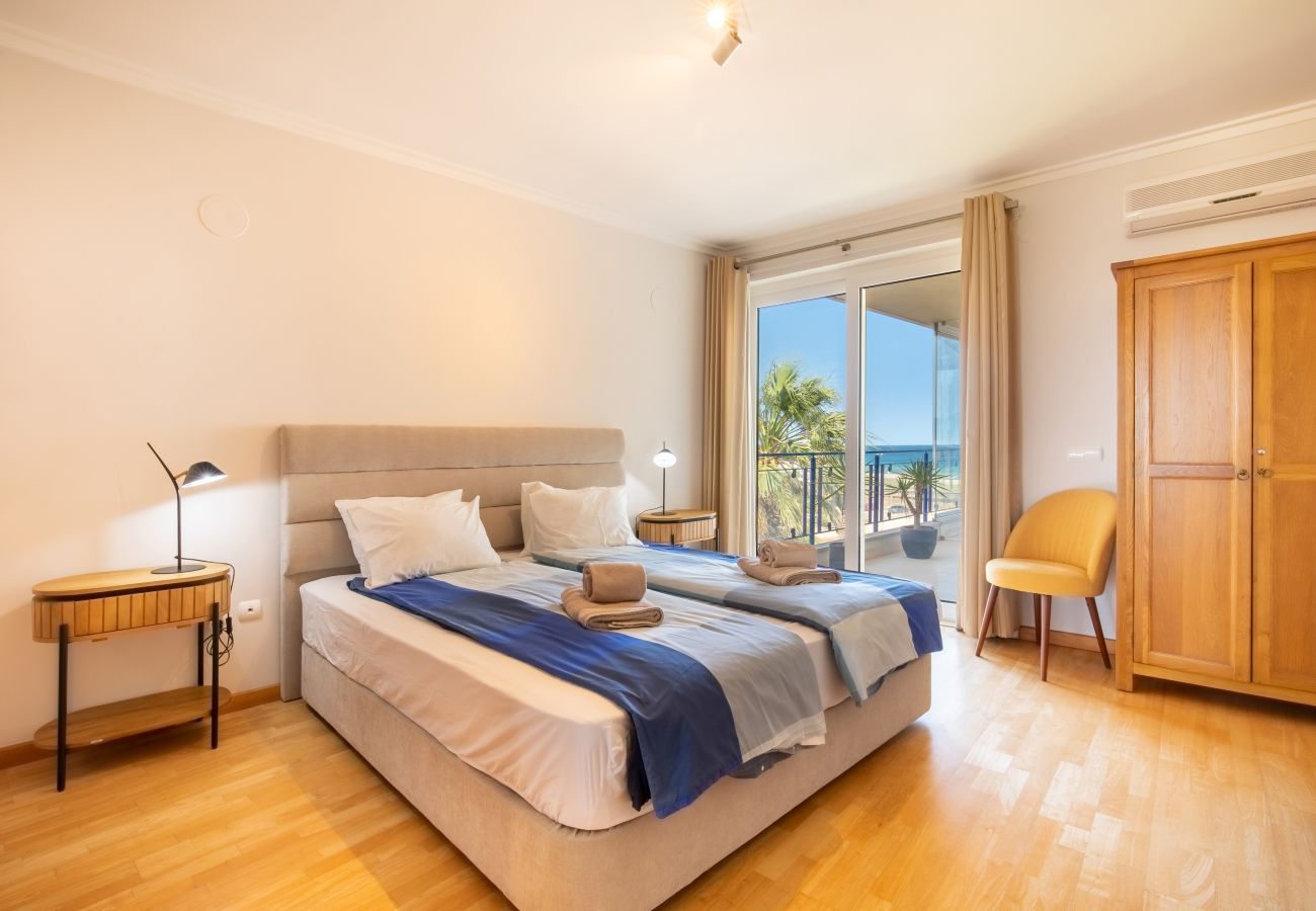 Komfortables Schlafzimmer mit Meerblick-Balkonzugang Schlafzimmer mit Doppelbett , Holzschrank und offener Balkontür mit Meerblick.